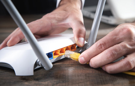 Man plugging internet cable into wifi router.