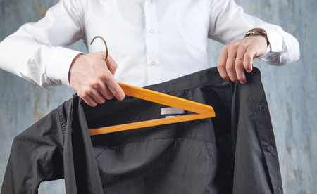 Businessman holding hanger with black shirt.の写真素材