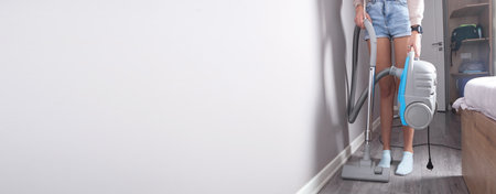Caucasian woman with a vacuum cleaner in home.の写真素材