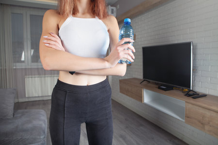 Woman holding bottle of water. exercise at homeの写真素材
