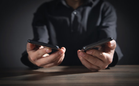 Businessman holding smartphones in office.の写真素材