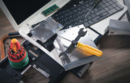 Broken laptop with a wrench and screwdriver on the table. computer repair service