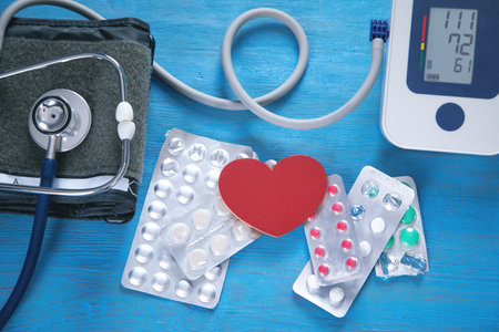 Stethoscope, blood pressure meter and pills on the blue background.