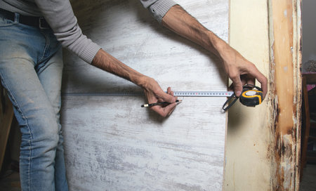 Carpenter marking laminate with tape measure and pencil.の写真素材
