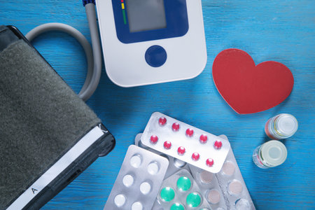 Blood pressure meter and pills on the blue background.