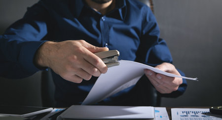 Man with a stapler connects the documents.の写真素材