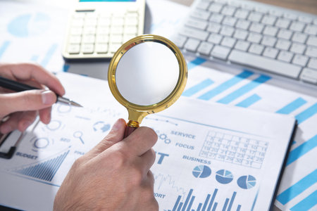 Man holding magnifying glass with graphs and charts. business. Analysis