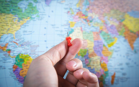 Male hand showing push pin on world map.の写真素材