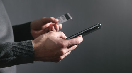 Man using smartphone and holding credit card.