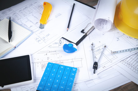 Architects workplace with architectural project plan and other objects.