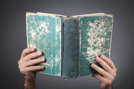 Male hands holding book on gray background.の写真素材