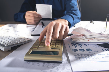 Businessman using calculator and holding bills. business