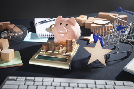 Piggy bank, coins, calculator, shopping cart on the table.の写真素材