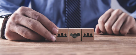 Man showing shaking hands and human icons on wooden cubes.
