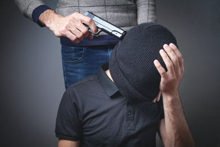 Person with a handgun aiming at a man head.の写真素材