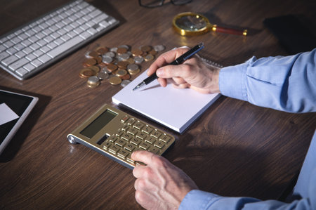 Businessman using calculator and writes in notepad.の写真素材