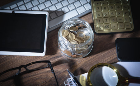 Jar of coins, calculator and other objects on the business desk.の写真素材