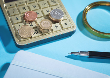 Coins, pen and calculator on the blue background.の写真素材