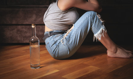 Young woman with a bottle of vodka at home.の写真素材