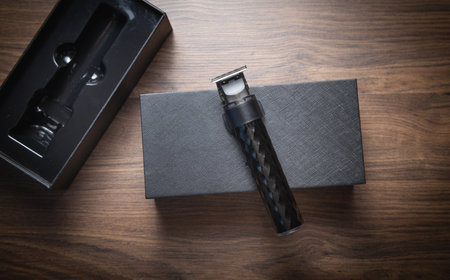 Black hair trimmer on wooden background.
