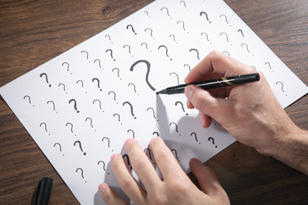Male hand draw question marks on paper.