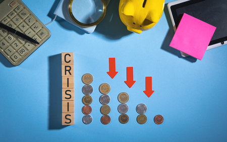 Coins, Crisis word, red arrows down and business objects on the blue background.の写真素材