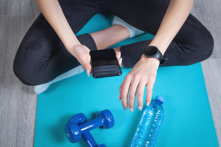 Woman using smart watch and smartphone at home.の写真素材