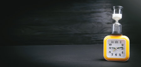 Yellow clock and hourglass on the dark background.