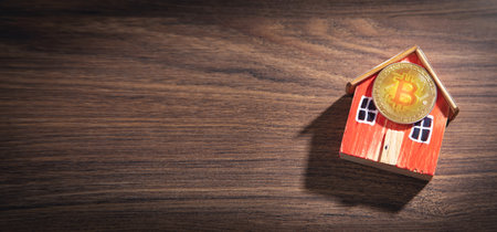 Bitcoin and house model on the wooden table.の写真素材
