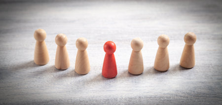 Wooden human figures on the white desk. leader
