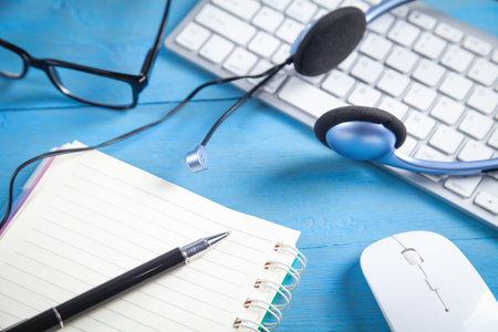 Customer service headset, computer keyboard and business objects on the blue background.の写真素材