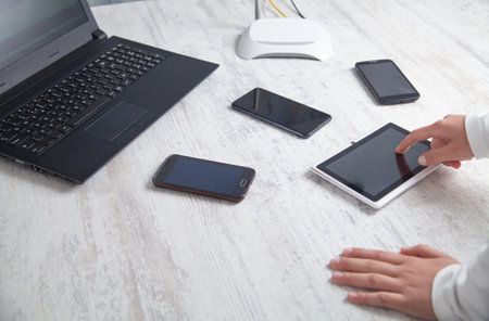 girl using tablet. Internet router with smartphones and laptop computer on the desk. Network,...