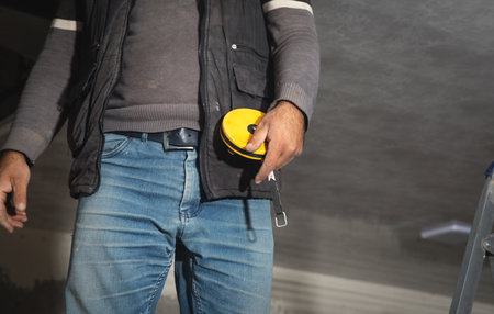 Caucasian worker holding measure tape.