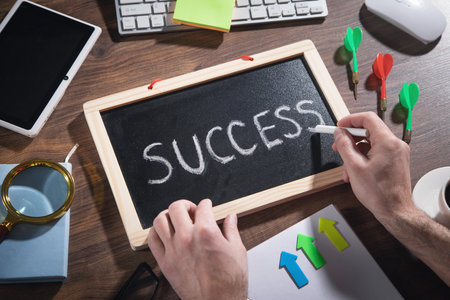Male hand draws Success text on blackboard with other objects.の写真素材