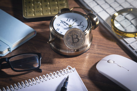 Bitcoin on clock with a calculator and other objects on the wooden table.の写真素材