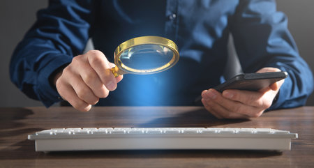 Man using magnifying glass over computer keyboard. Concept of searching internetの写真素材