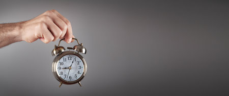 Male hand holding alarm clock.