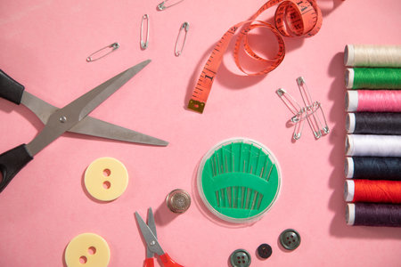 Sewing tools on the pink paper background.