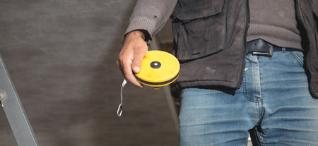 Caucasian worker holding measure tape.