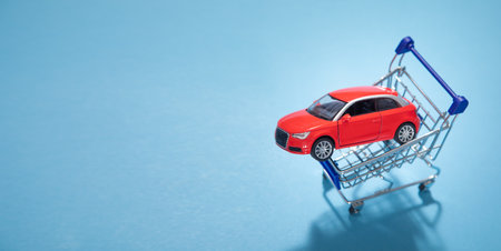 Toy red car with a shopping cart on the blue background.の写真素材