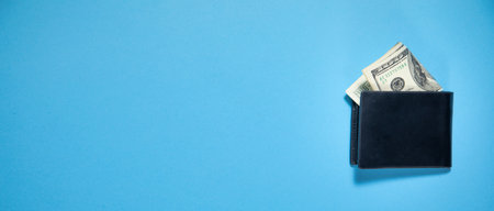 Black wallet with a dollar banknotes on the blue background.の写真素材