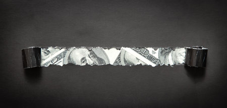 Hole ripped in paper with a dollar.