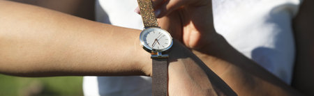 Caucasian girl with a wristwatch in hand.