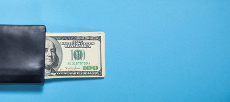 Black wallet with a dollar banknotes on the blue background.の写真素材