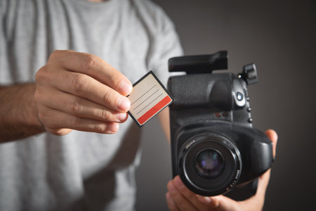 Photographer holding memory card insert DSLR camera.の写真素材