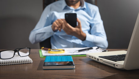 Focus on calculator with a man using smartphone.の写真素材