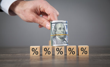 Male hand showing dollar and percent symbols on wooden cubes.
