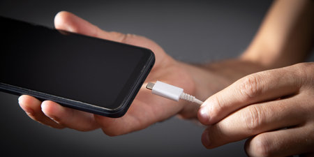 Man connecting charger cable to mobile phone.の写真素材