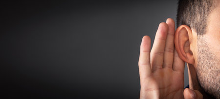 Caucasian man hold hand near ear. Trying to hear a gossipの写真素材