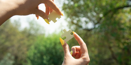 Woman holding a piece of wooden jigsaw puzzle together in the outdoors.の写真素材